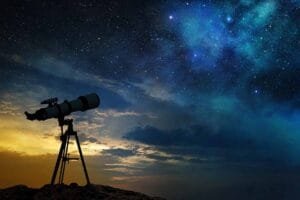 A telescope on a tripod pointed towards the starry night sky